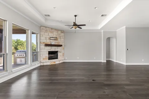 a view of a livingroom with wooden floor a ceiling fan and windows