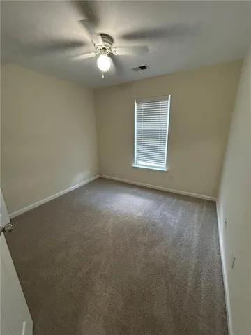 an empty room with a chandelier fan and windows