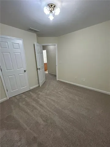 an empty room with chandelier fan and windows