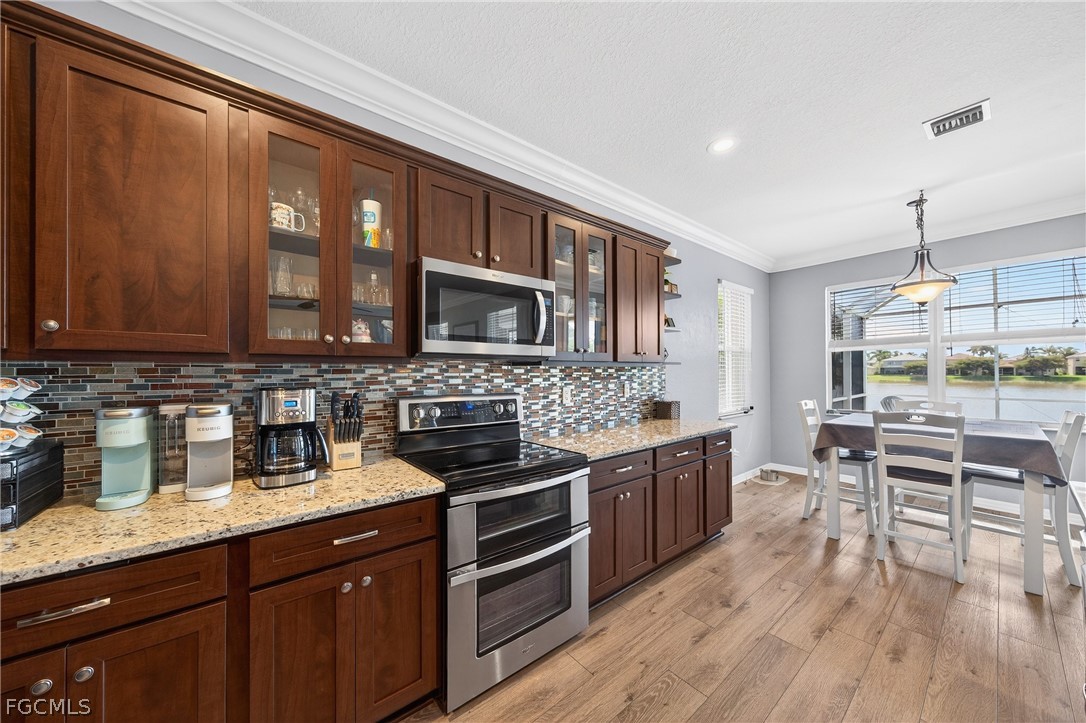 8313 Sumner Avenue Fort Myers, FL 33908 - Photo 13 of 42 a kitchen with stainless steel appliances granite countertop a stove top oven a sink dishwasher a dining table and chairs with wooden floor