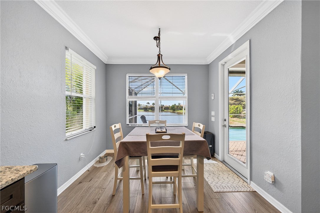 8313 Sumner Avenue Fort Myers, FL 33908 - Photo 16 of 42 a dining room with wooden floor a chandelier a wooden table and chairs