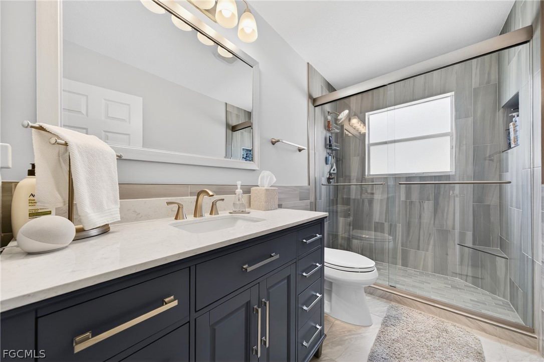 8313 Sumner Avenue Fort Myers, FL 33908 - Photo 24 of 42 a bathroom with a granite countertop sink mirror vanity and toilet
