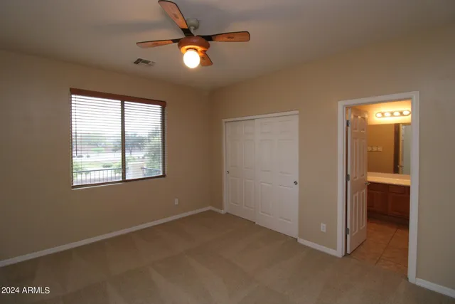 a view of an empty room with window and chandelier fan