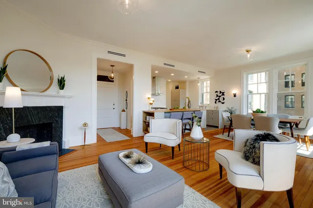 a living room with furniture a fireplace a rug and kitchen view
