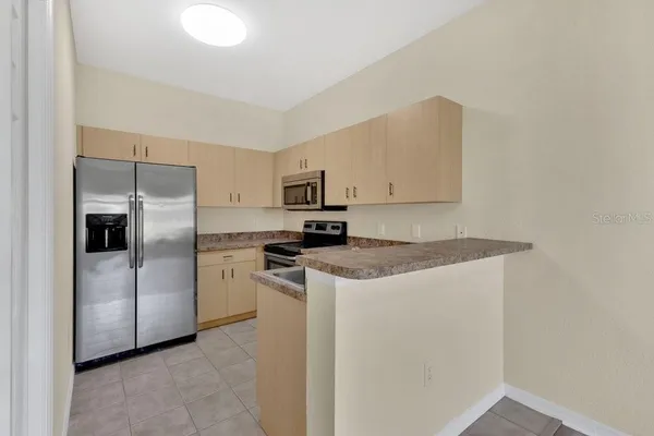 a kitchen with stainless steel appliances granite countertop a refrigerator a stove a sink and white cabinets