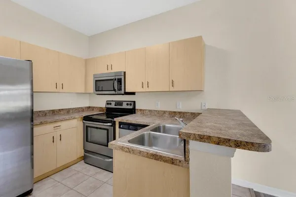 a kitchen with granite countertop a sink stove and microwave