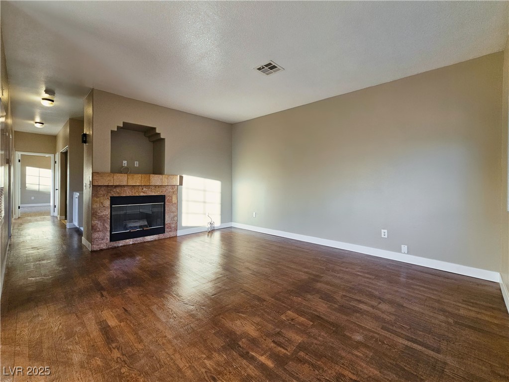 1851 Hillpointe Road, Unit 2124 Henderson, NV 89074 - Photo 13 of 24 Unfurnished living room with baseboards, dark wood-style flooring, a tiled fireplace, and visible vents