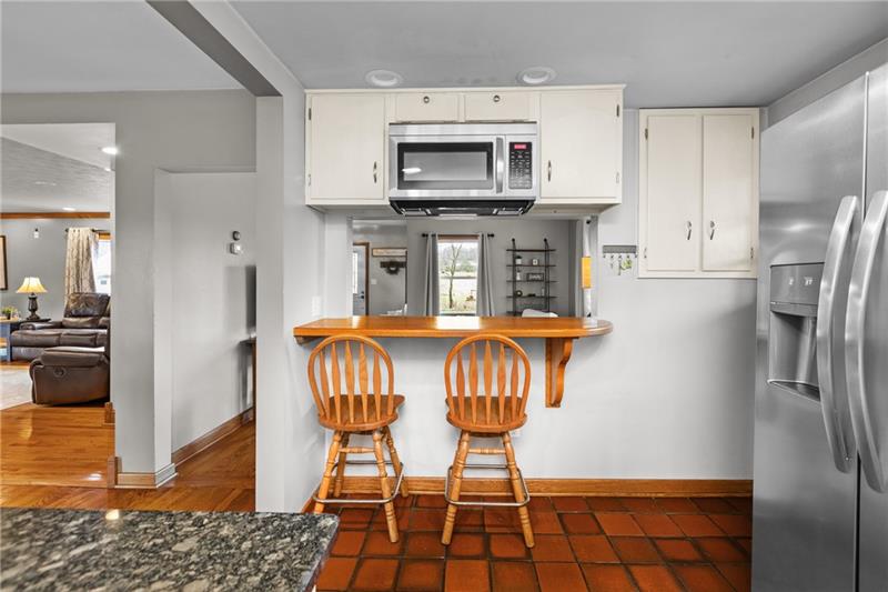 100 Daugherty Road Grove City, PA 16127 - Photo 10 of 48 a kitchen with stainless steel appliances a refrigerator a stove a microwave oven a dining table and chairs with wooden floor