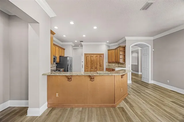 a view of kitchen with stainless steel appliances granite countertop a stove and a wooden floors