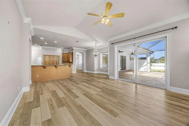 a view of an empty room with wooden floor and a kitchen