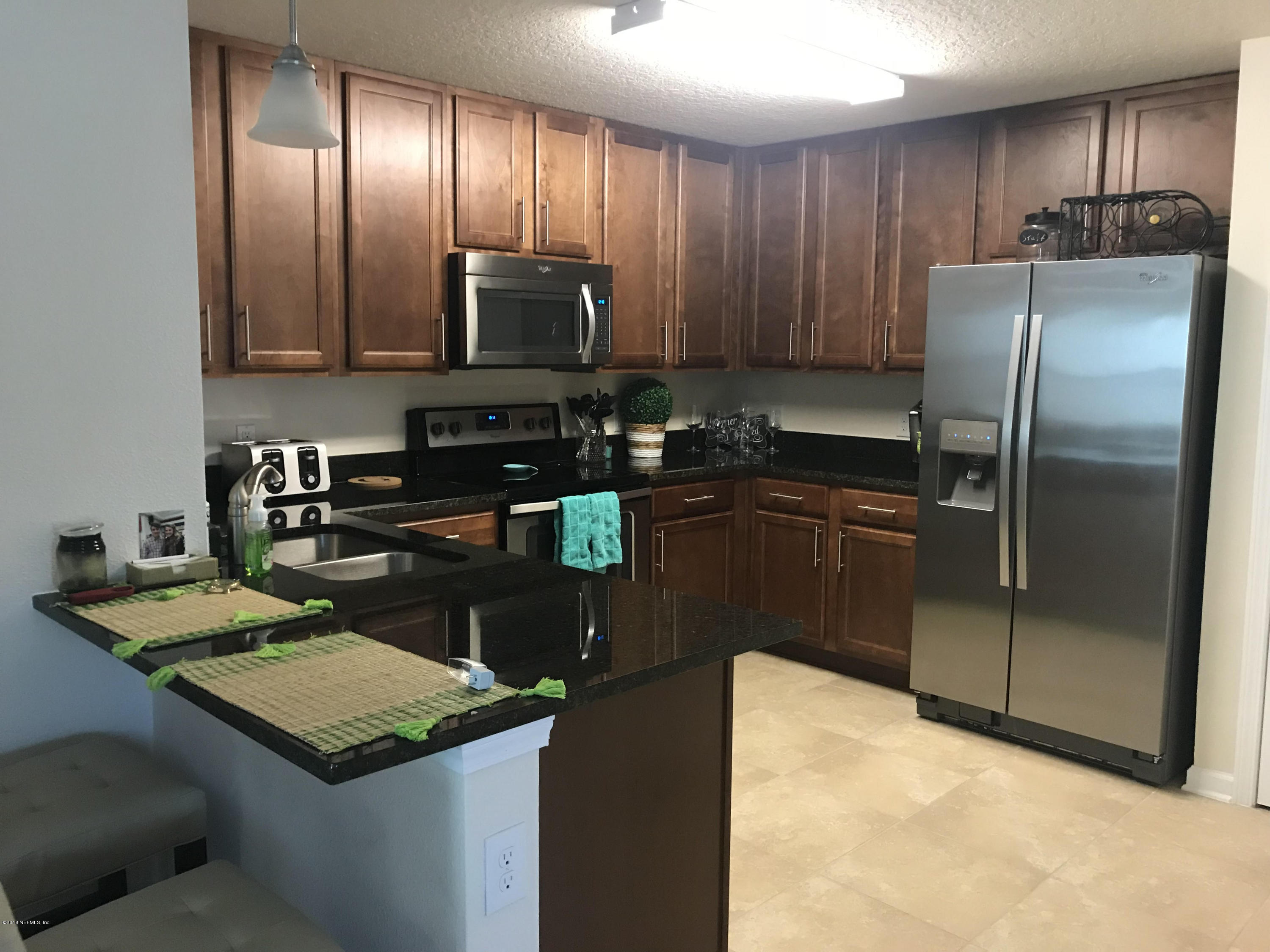 218 Larkin Place, Unit 111 St. Johns, FL 32259 - Photo 1 of 21 a kitchen with kitchen island granite countertop stainless steel appliances and wooden cabinets