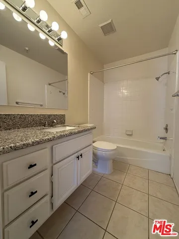 a bathroom with a granite countertop sink a toilet and bathtub