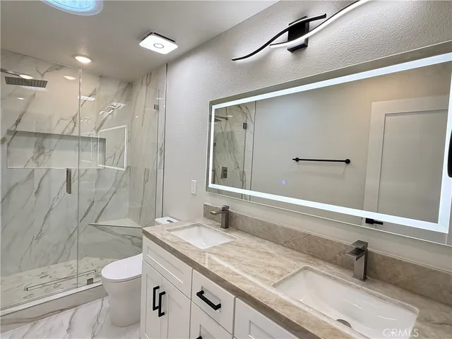 a bathroom with a granite countertop toilet sink vanity and mirror