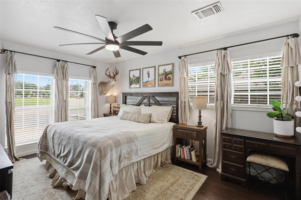 308 West 1st Street Springtown, TX 76082 - Photo 21 of 39 Bedroom featuring three windows with blinds and drapes, dark wood-finish flooring, and a ceiling fan with integrated lighting