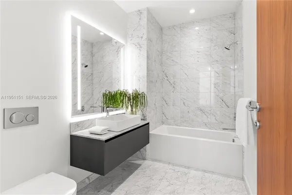 a bathroom with a granite countertop sink a toilet a tub and shower