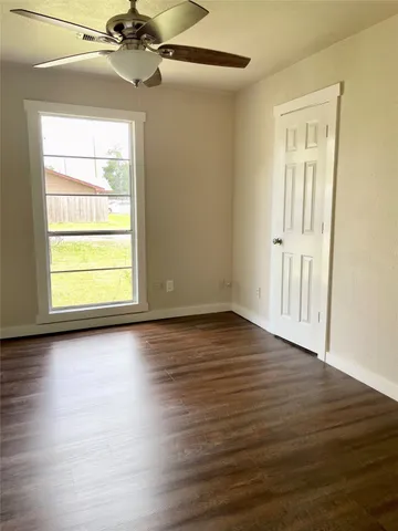 an empty room with wooden floor staircase and windows
