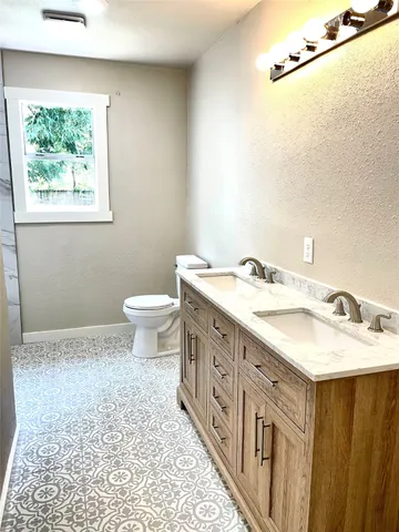 a bathroom with a double vanity sink toilet and a mirror