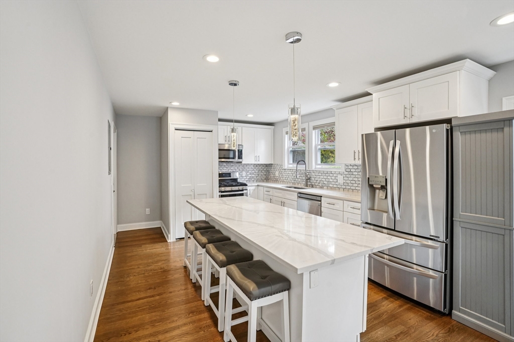 33 Slade Street, Unit 1 Belmont, MA 02478 - Photo 11 of 26 a kitchen with kitchen island white cabinets and stainless steel appliances