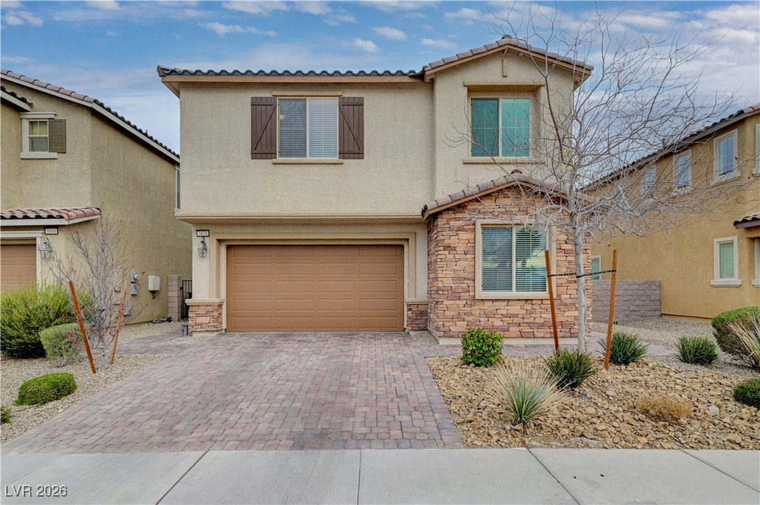 3826 Asia Road North Las Vegas, NV 89032 - Photo 2 of 30 Mediterranean / spanish house with stone siding, stucco siding, decorative driveway, a garage, and a tiled roof