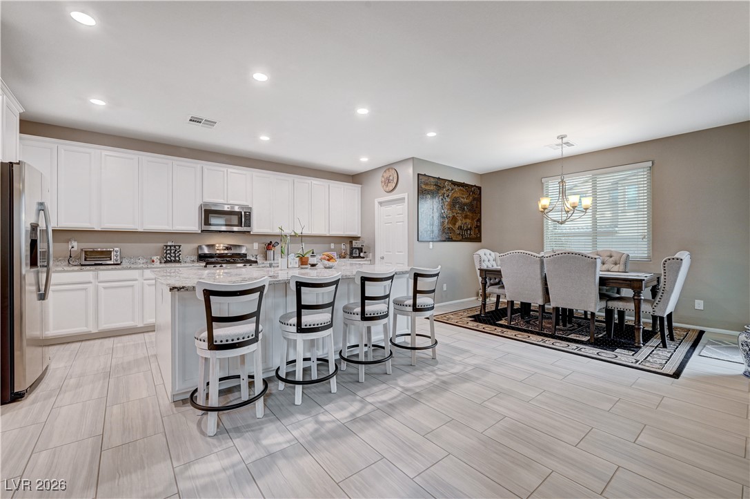 3826 Asia Road North Las Vegas, NV 89032 - Photo 9 of 30 Kitchen with a breakfast bar area, white cabinets, recessed lighting, appliances with stainless steel finishes, and a center island with sink