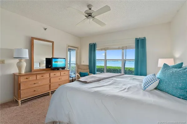 a bedroom with a large bed and a flat tv screen on dresser