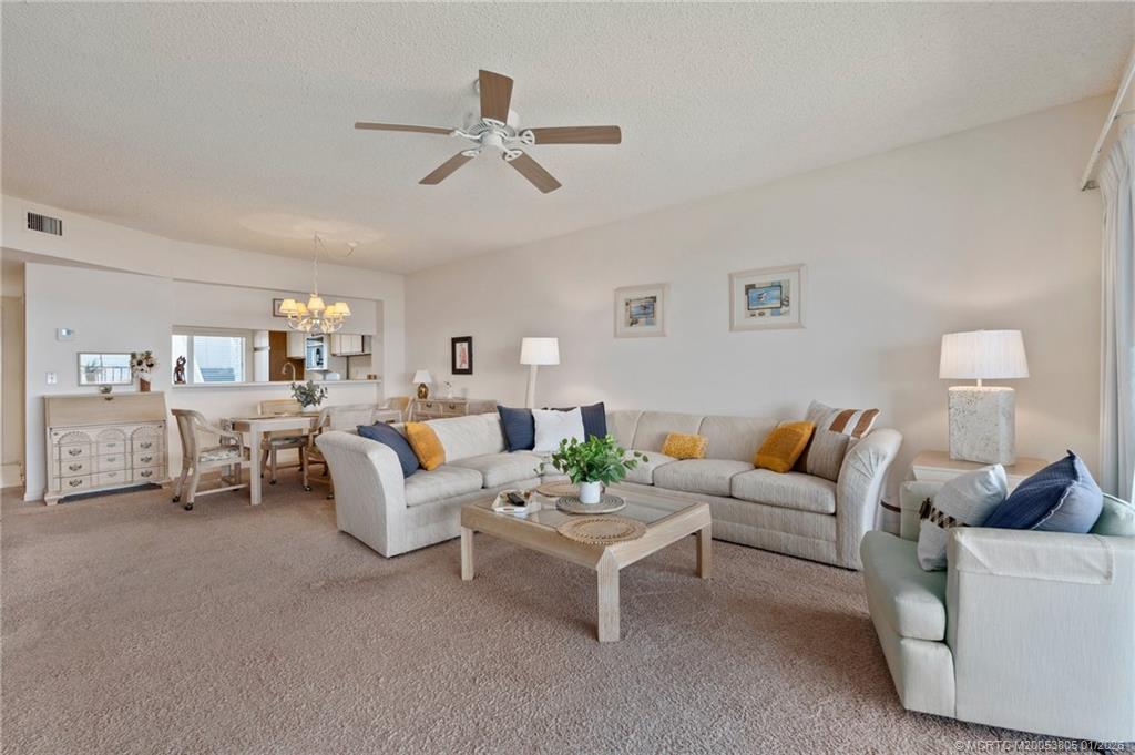 164 Northeast Edgewater Drive, Unit 2105 Jensen Beach, FL 34957 - Photo 19 of 35 a living room with furniture and a chandelier