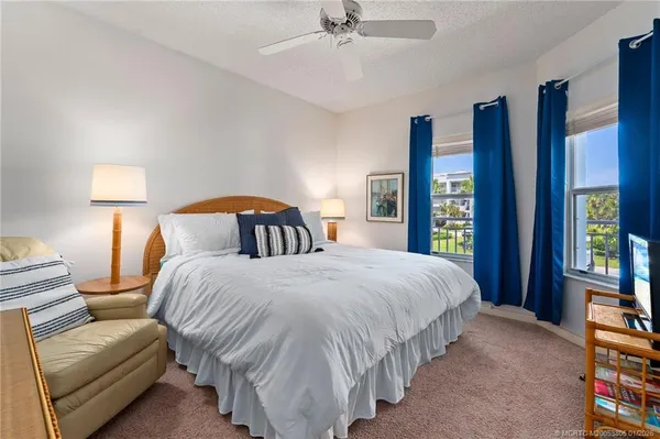 a bedroom with bed and a large mirror next to a window