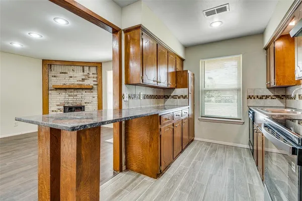 a kitchen with stainless steel appliances granite countertop a stove a sink dishwasher and a refrigerator with wooden floor
