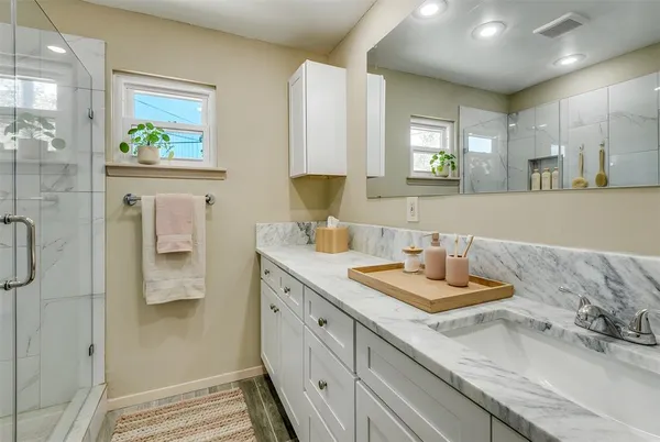 a bathroom with a granite countertop double vanity sink a mirror and a shower