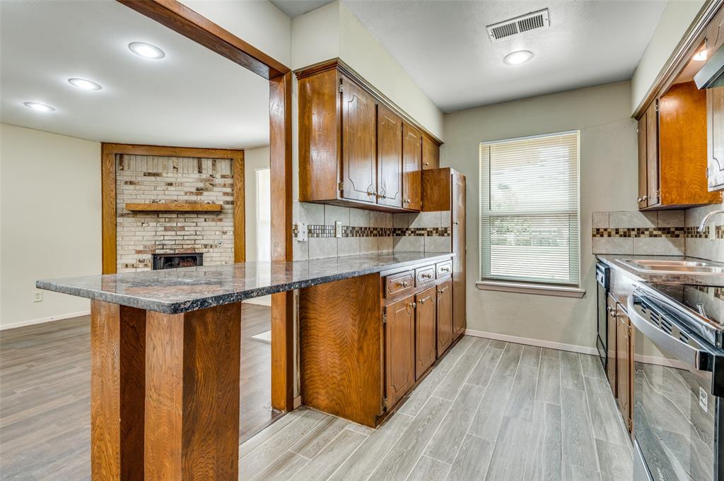 110 Crandall Road Irving, TX 75060 - Photo 4 of 13 a kitchen with stainless steel appliances granite countertop a stove a sink dishwasher and a refrigerator with wooden floor
