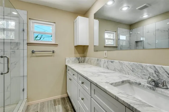 a bathroom with a granite countertop sink a mirror and a shower