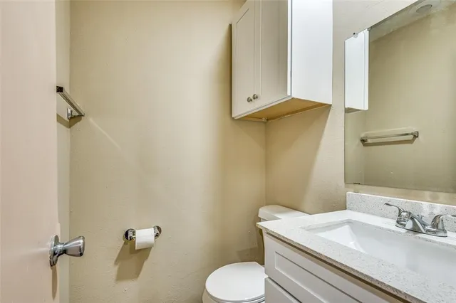 a bathroom with a granite countertop toilet sink and mirror