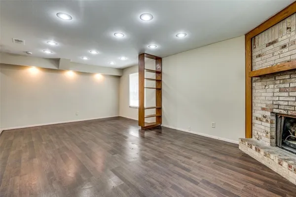 a view of an empty room with wooden floor and a fireplace
