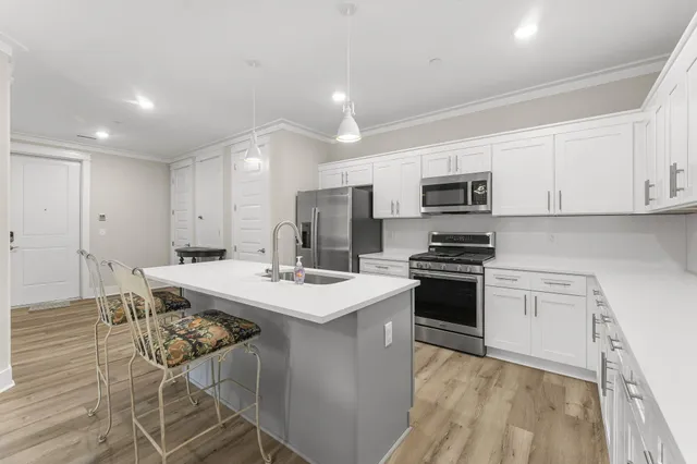 a open kitchen with stainless steel appliances granite countertop a stove top oven a sink dishwasher and white cabinets with wooden floor