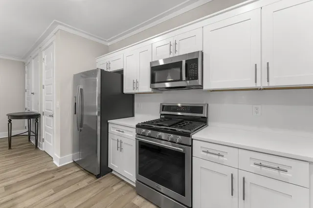 a kitchen with stainless steel appliances white cabinets and a stove a microwave oven with wooden floor