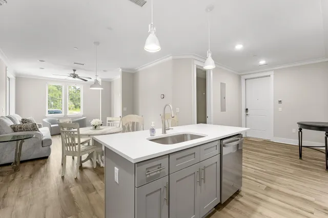 a hall with kitchen island a sink dishwasher a dining table and chairs with wooden floor