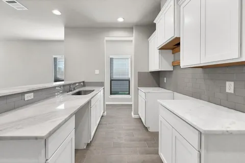 a kitchen with granite countertop a sink and dishwasher a stove top oven with white cabinets
