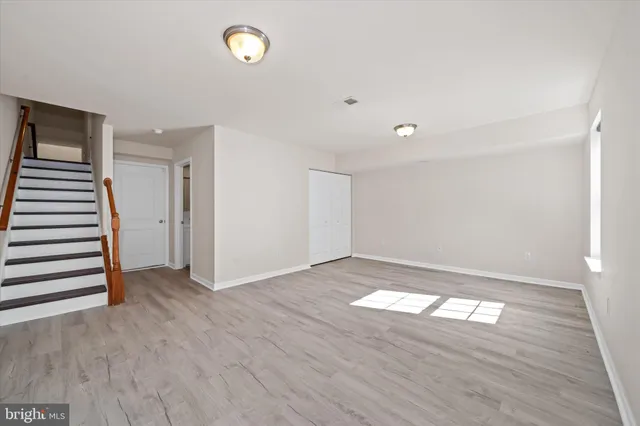 a view of empty room with wooden floor and window