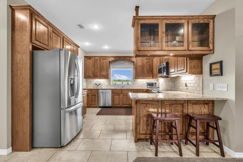 613 Bone Road Valley Mills, TX 76689 - Photo 11 of 40 a kitchen with kitchen island granite countertop wooden cabinets and stainless steel appliances
