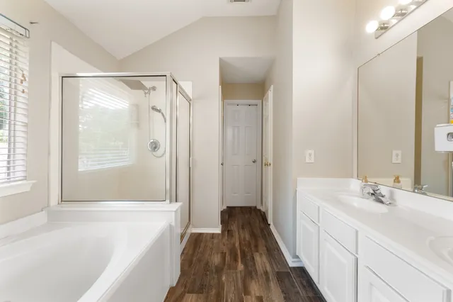 a bathroom with a double vanity sink a mirror and a bathtub