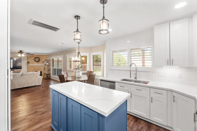a kitchen with sink stove and white cabinets with wooden floor
