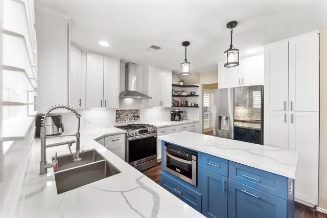 a kitchen with stainless steel appliances granite countertop a stove a refrigerator and a sink with wooden floor