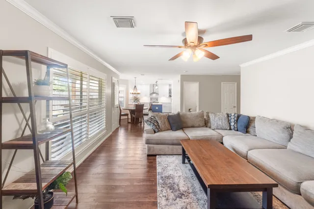 a living room with furniture a ceiling fan and a large window