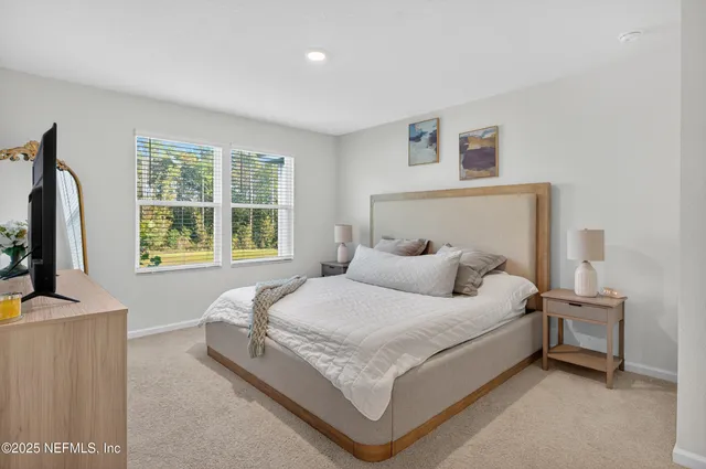 a bedroom with a bed and a flat screen tv in white walls
