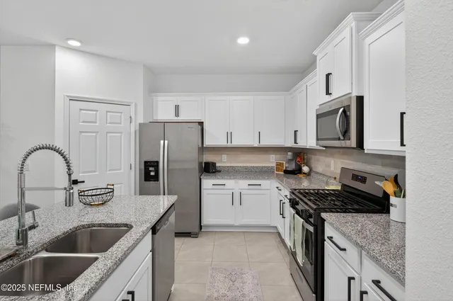 a kitchen with a refrigerator a stove a sink and white cabinets with wooden floor