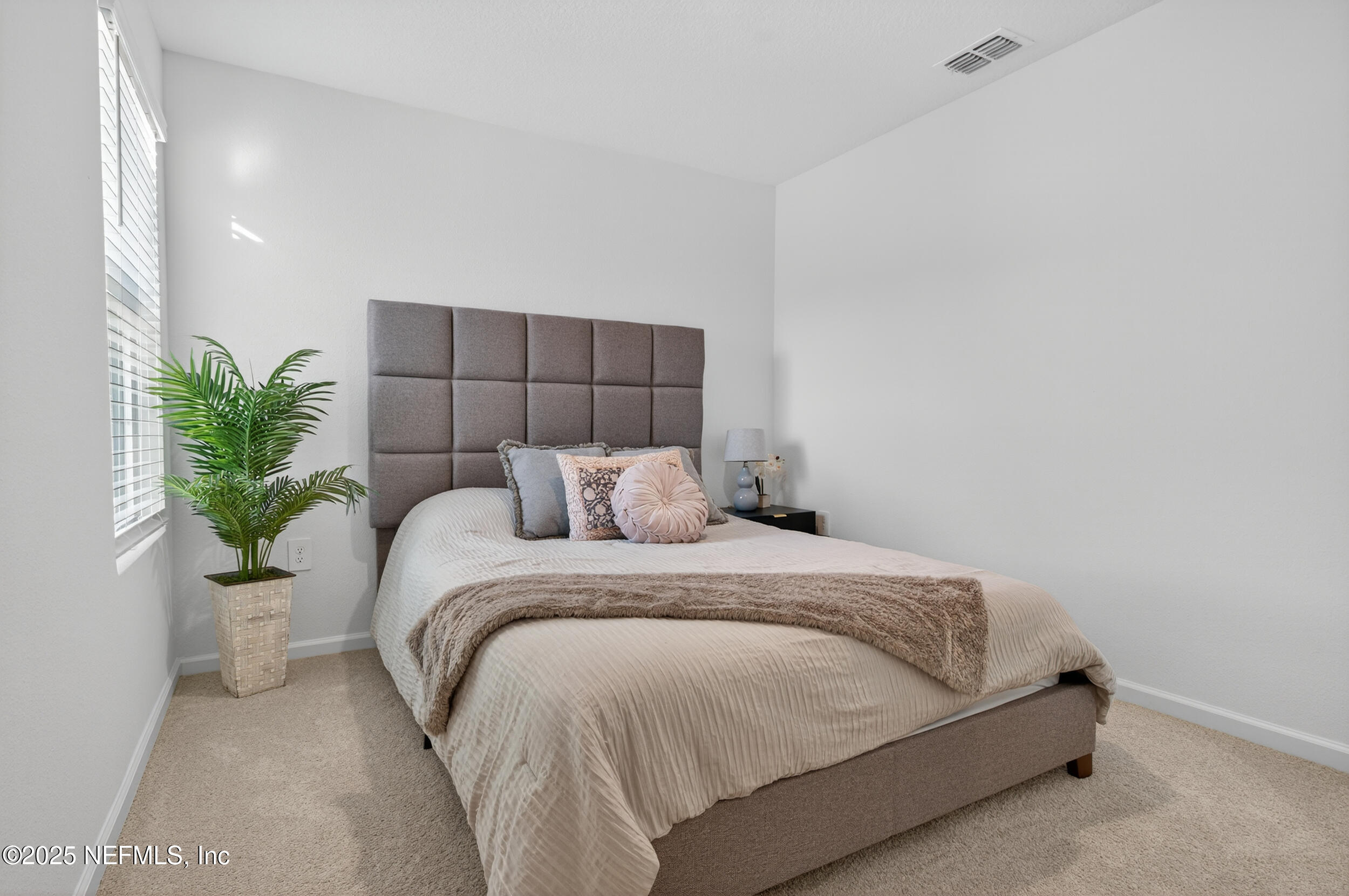 33 Coastline Way St. Augustine, FL 32092 - Photo 31 of 35 a spacious bedroom with a bed and a potted plant