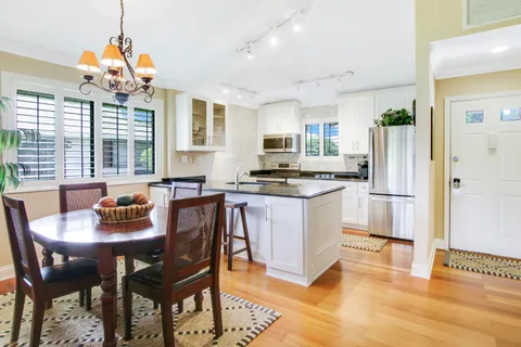 a kitchen with stainless steel appliances granite countertop a stove a refrigerator a kitchen island a dining table and chairs