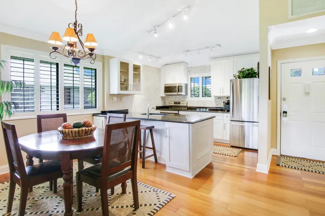 a kitchen with stainless steel appliances granite countertop a stove a refrigerator a kitchen island a dining table and chairs