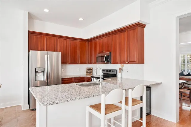 a kitchen with stainless steel appliances granite countertop a table chairs in it and wooden floors