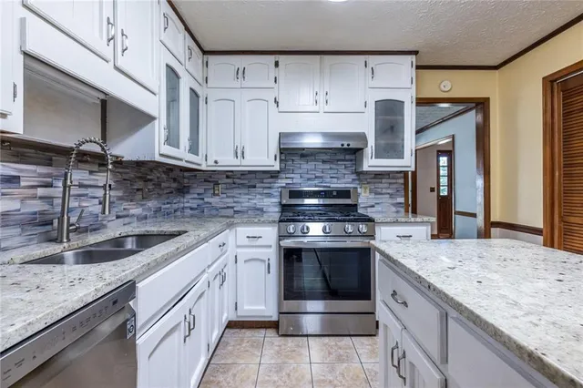 a kitchen with stainless steel appliances granite countertop a sink stove and cabinets